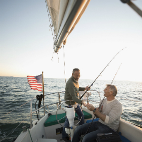 Two men in stern of sailboat on ocean fishing