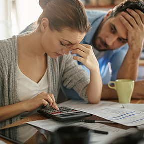 Young couple in kitchen, appearing distressed by figures woman is calculating